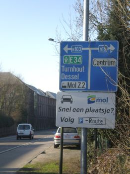 Foto van voorwegwijzerbord met daaronder wit onderbord waarop onder meer staat: Snel een plaatsje? Volg P-route.